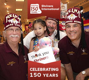 Shriners com um paciente segurando um cartaz de Obrigado Shriners