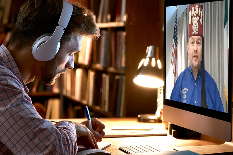 Man with headphones on listening to and watching webinar
