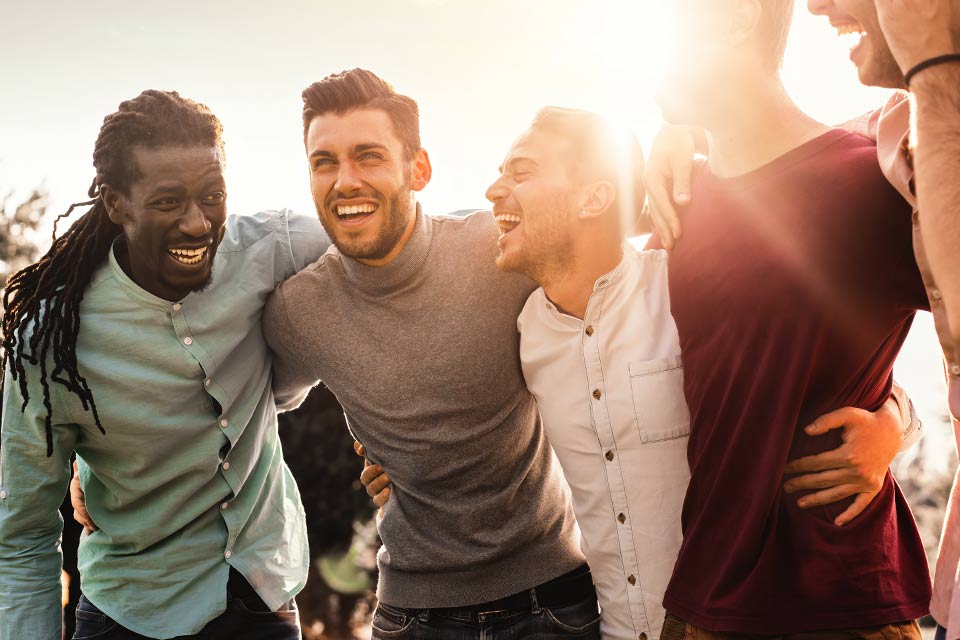 five men laughing with the sun behind them.