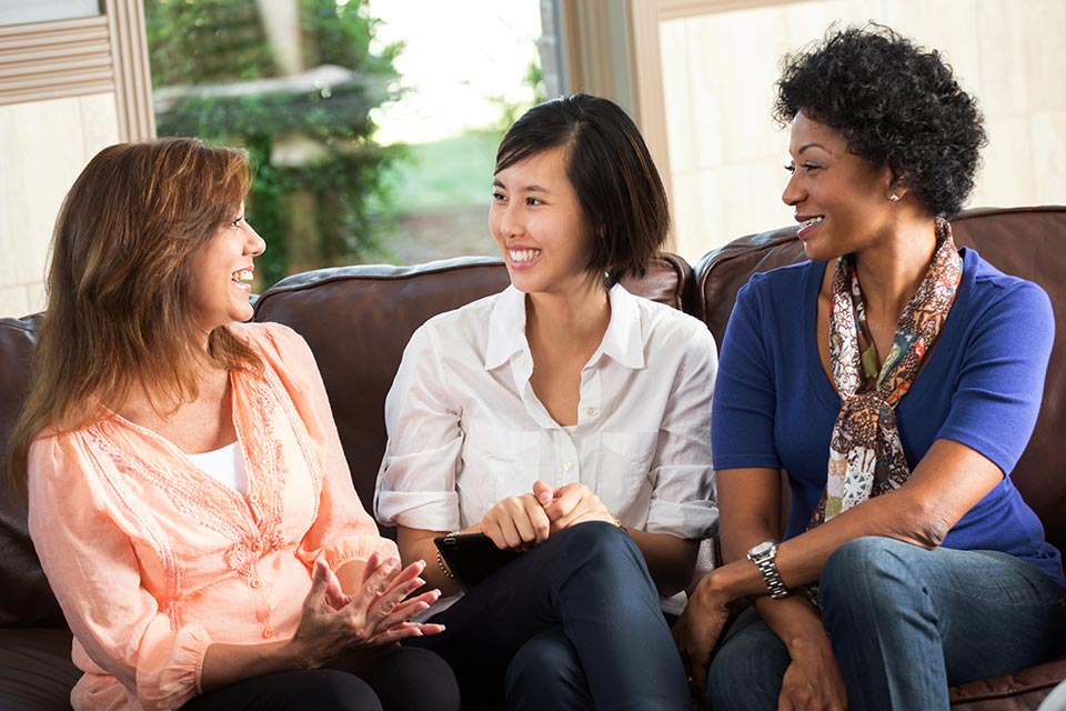 three women sitting on sofa chatting