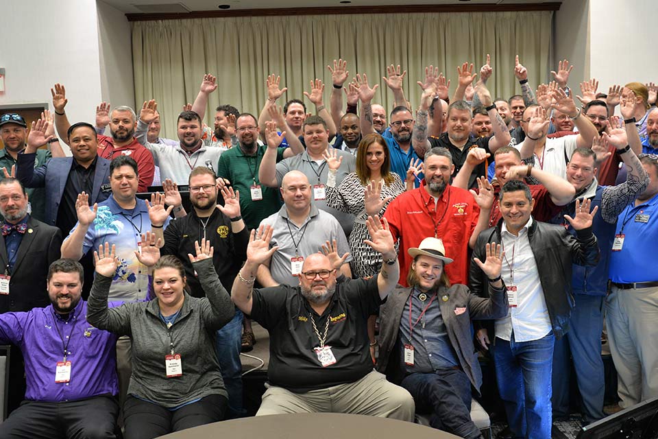 Large group of men and women with arms raised in the air