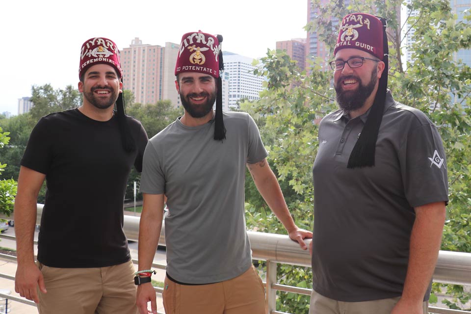 Tres Ziyara Shriners parados afuera con el horizonte de fondo