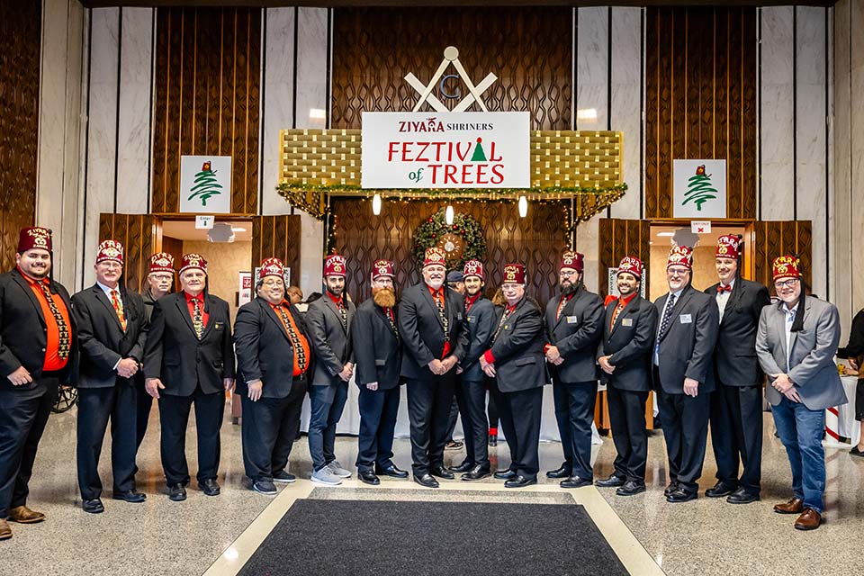 Large group of Shriners, Ziyara Shriners Feztival of Trees sign in background