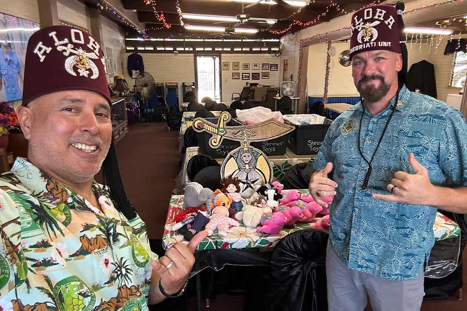 Dos Aloha Shriners frente a un stand.