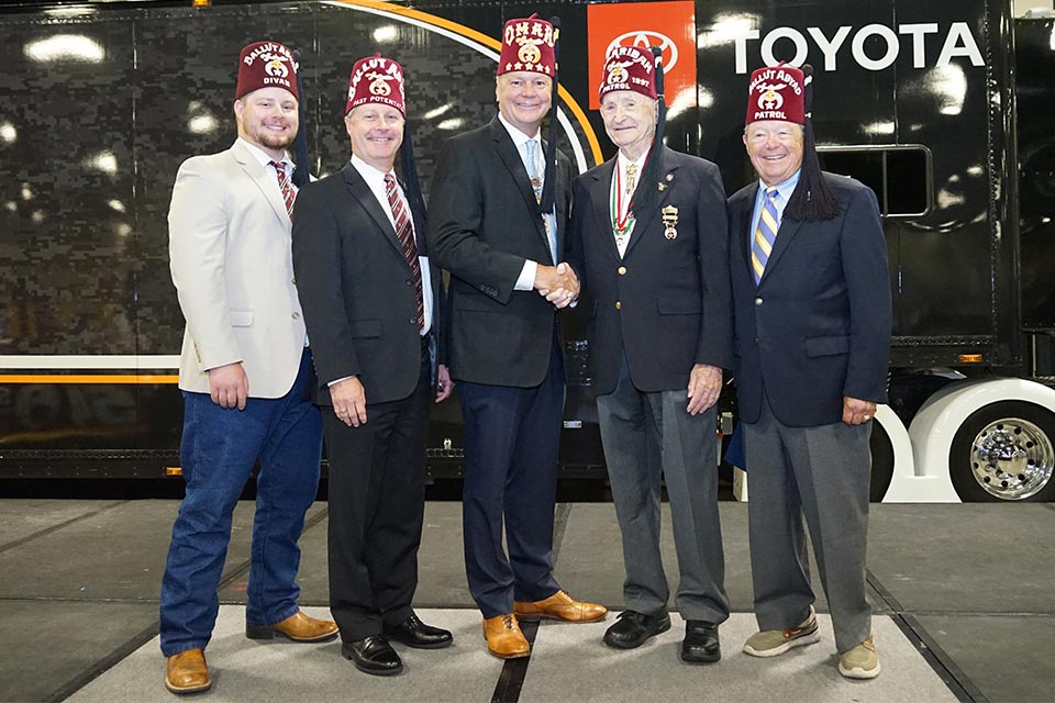 trois hommes portant des costumes et des fez disposés autour de deux hommes se serrant la main