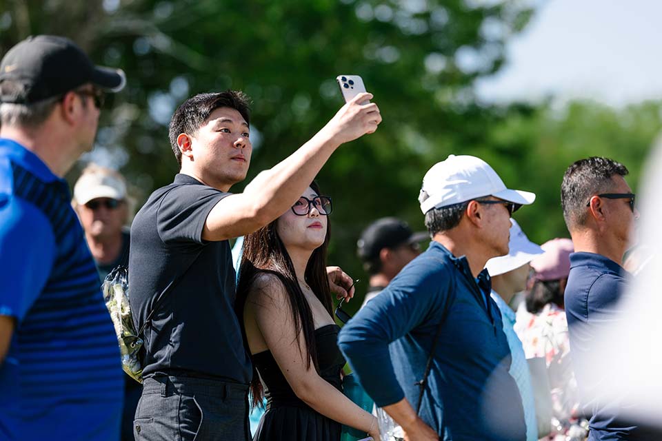 Un hombre y una mujer se toman un selfie rodeados de mucha gente.