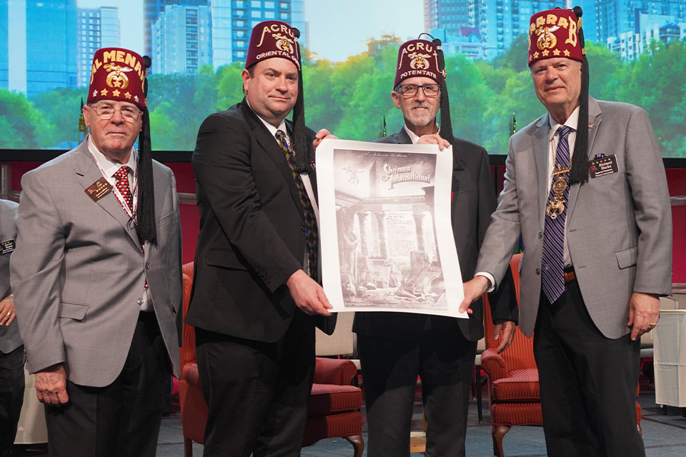 four men in fezzes holding a large document on a stage
