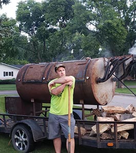 man in front of large bbq smoker drum