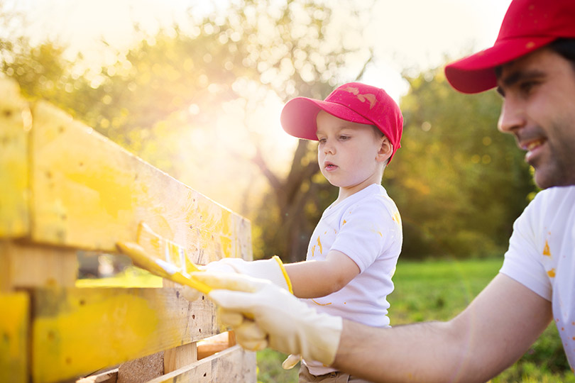 father and son painting fence